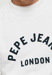 Bílá mikina s archovým černým potiskem s textem "PEPE JEANS LONDON." Hladká tkanina s žebrovaným výstřihem.