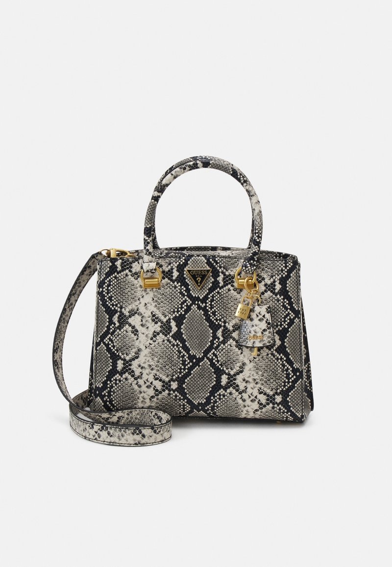 Sac à main noir et blanc à motif serpent avec deux poignées, bandoulière amovible et logo Guess ainsi que des breloques en ton or.