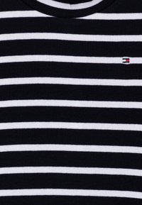 Schwarz-weiß gestreiftes T-Shirt mit gerippter Textur, Rundhalsausschnitt und kleinem Logo auf der linken Brustseite.