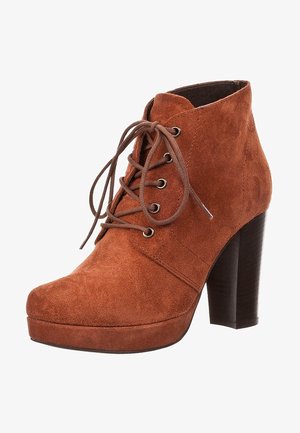 Botín de ante marrón hasta el tobillo con cordones en la parte delantera, puntera redondeada, suela con plataforma y tacón alto y grueso.
