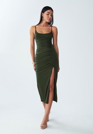 Olive green midi dress with ruching, thin straps, and side slit. Smooth, stretchy fabric with a fitted design, ideal for formal or casual wear.