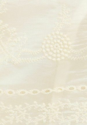 Crèmekleurige stof met fijne bloem- en cirkelvormige borduurpatronen in licht verheven borduurgaren.