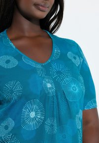 Top de escote en V color verde azulado con estampado floral y geométrico en blanco. Mangas cortas y detalle plisado, fabricado con un material suave y de textura lisa.