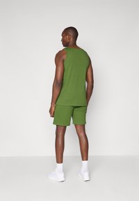 Camisola verde de alças e calções em mistura de algodão. Design simples, ajuste descontraído, combinados com ténis brancos e meias.