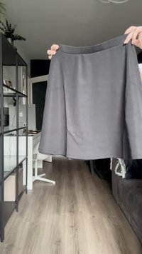 Pilkos, iki kelių besiekiančios sijono, pagaminto iš lygaus audinio, su paprastu A formos dizainu ir tvirta juosta, laikomo asmens.