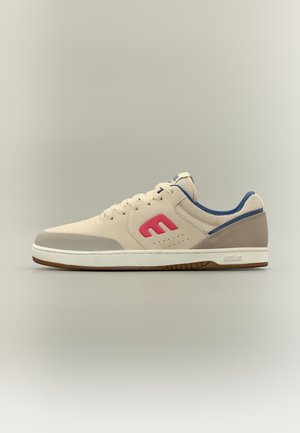 Beiger Sneaker mit niedrigem Schaft, rotem "E"-Logo, blauem Innenfutter, weißer Sohle und beige-grauem Farbverlauf im Zehenbereich.