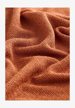 Rudai spalvos tekstūruota medžiaga su audiniu raštu, demonstruojanti švelnias klostes ir minkštą, jaukią išvaizdą. Tinka drabužiams ar namų tekstilėms.