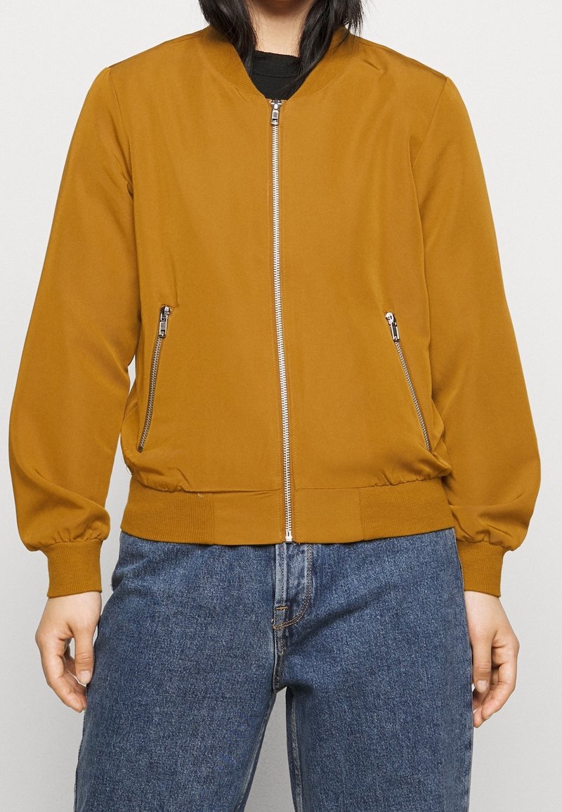 Musztardowa kurtka bomberka z zamkiem z przodu, ściągaczami na mankietach i dwoma bocznymi kieszeniami na zamek; gładka faktura i dopasowany krój.