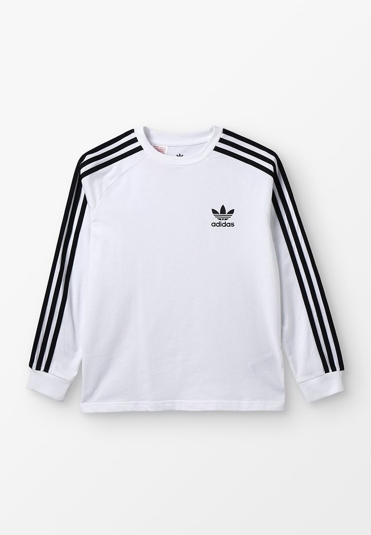 Maglietta bianca Adidas a maniche lunghe con dettagli a tre strisce nere sulle maniche e logo trefoil Adidas sul petto sinistro.