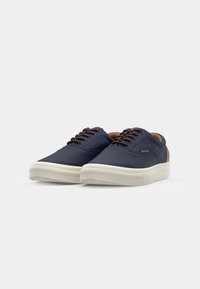 Navy canvas sneakers with a rubber sole, brown accents on the heel, and brown lace-up design. Smooth texture with minimal detailing.