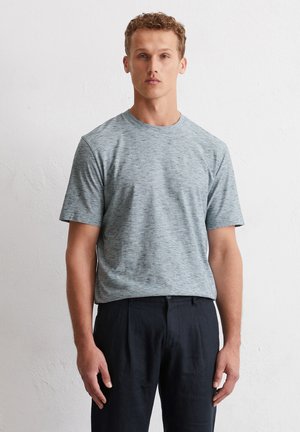 T-shirt en coton gris marbré avec un col rond et des manches courtes, associé à un pantalon sombre. Design simple, coupe normale et texture douce.