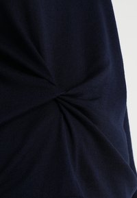 Tissu en maille bleu marine présentant un détail de design torsadé, créant texture et dimension. Fini lisse avec une apparence douce.