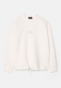 Sudadera crema con cuello redondo, mangas largas y dobladillo con cordón. Presenta un sutil logo en relieve en el pecho. Textura suave.