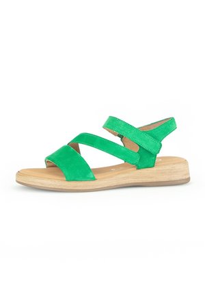 Sandale en daim vert pour femme avec trois brides et une semelle plate en bois clair, vue de côté sur fond blanc.