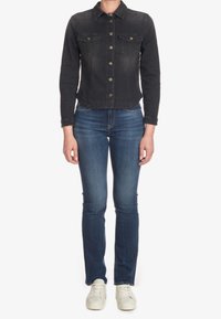 Svart denimjacka med knäppning, två bröstfickor och krage. Matchad med medelblå slim-fit jeans och vita sneakers.