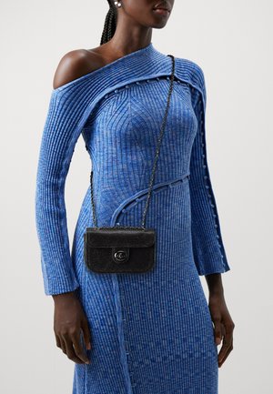 Robe bleue côtelée avec un design bardot et des accents de boutons, associée à un petit sac à main noir texturé avec une chaîne.