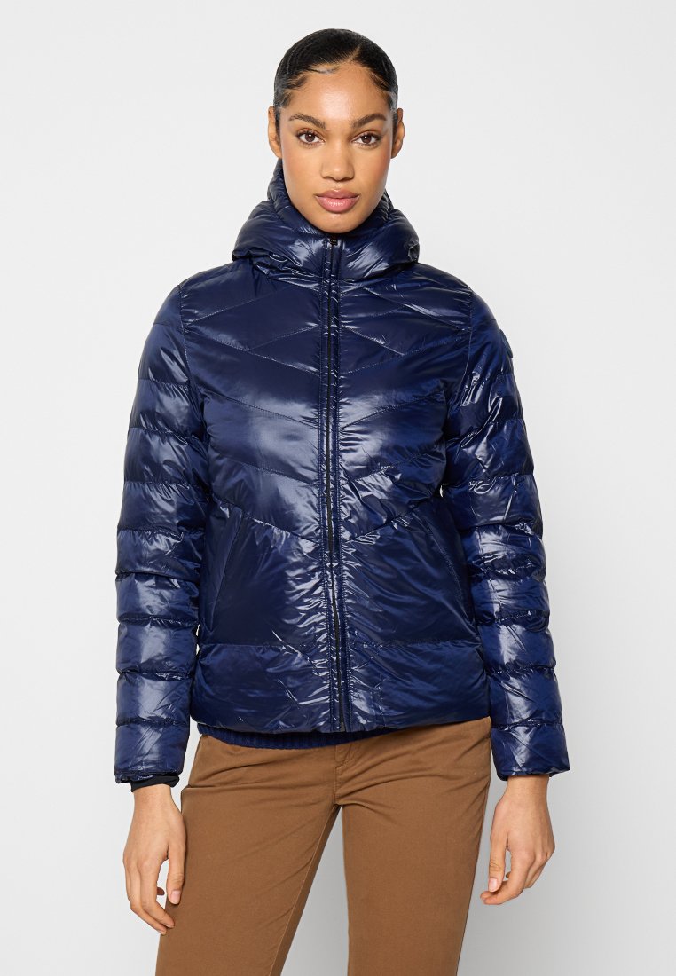 Navyblaue Steppjacke mit glänzender Oberfläche, diamantgequiltetem Design und hohem Kragen. Mit einem zentralen Reißverschluss und elastischen Bündchen.
