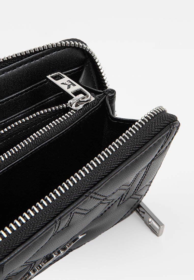 Czarny portfel na zamek wykonany z fakturowanej skóry, z metalowymi elementami w kolorze srebra, posiadający dwie przegrody i pikowaną powierzchnię.