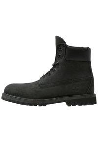 Stivaletti alla caviglia in suede nero con punta rotonda, allacciatura frontale e colletto imbottito; presentano un logo sul lato esterno e suola in gomma resistente.