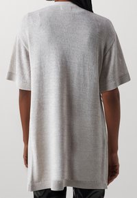 Ljusgrå överdimensionerad stickad topp med korta ärmar, ribbade muddar och en avslappnad passform. Slät textur med en subtil glans.