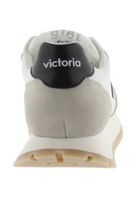 White and gray sneaker with a suede back, black leather accent on heel, textured sole, and logo "victoria" in white on black.