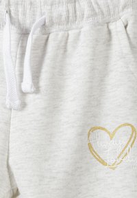 Grå sweatpants gjorda av mjukt tyg, med en vit dragsko och en guldig hjärtgrafik med texten "Always Lovely."
