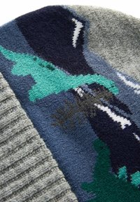 Bonnet en tricot présentant des motifs géométriques multicolores dans des fils bleu foncé, vert et gris, avec un bandeau côtelé texturé.