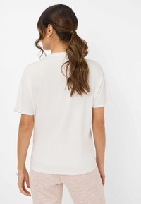 Leichtes, cremefarbenes T-Shirt mit kurzen Ärmeln und rundem Halsausschnitt. Glatte Textur, lässige Passform und keine auffälligen Designelemente.