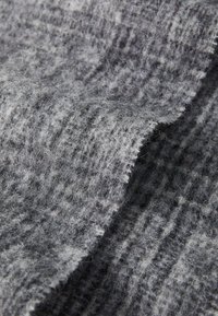 Wollstoff in Grautönen mit einer weichen, kuscheligen Textur. Besitzt ein dezentes Karomuster, das das gewebte Design hervorhebt.