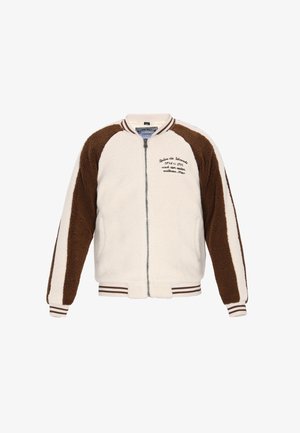 Měkká krémově zbarvená bunda s hnědými doplňky. Má zipové zapínání, žebrovaný límec a manžety a šití na hrudi.