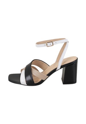Sandales à talons carrés en cuir noir et blanc avec un orteil carré, dotées de brides entrecroisées et d'une sangle de cheville réglable.
