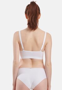 Bralette blanche et culotte assortie en tissu lisse. La bralette a des bretelles réglables et un design sans couture, offrant un look minimal.