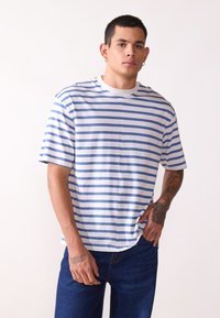 Camiseta a rayas en azul y blanco, fabricada en tejido suave. Presenta un escote redondo y mangas cortas, con un ajuste relajado.
