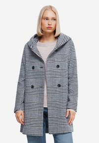 Geruite jas in zwart en witte stof, met een capuchon, dubbele knopen en een relaxte pasvorm. Draag het over een lichte top en jeans.