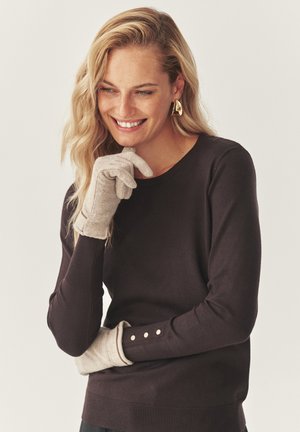 Pull marron à col rond et poignets côtelés, associé à des gants gris clair dotés d'un design ajusté et de boutons décoratifs au poignet.