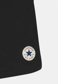 Pantalones cortos negros con un logo circular en blanco y rojo de "Converse All Star" con una estrella azul. Tejido suave con una cinturilla elástica.