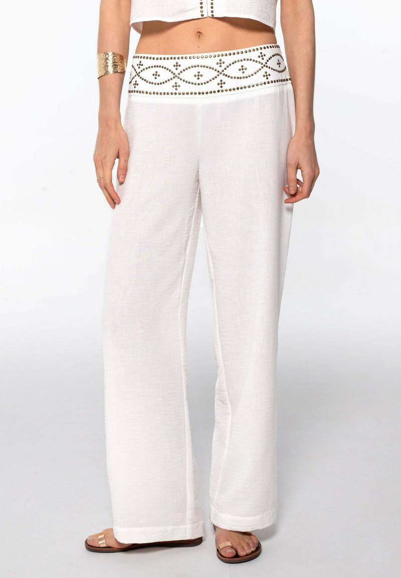 Pantalones de lino blancos de pierna ancha con una cinturilla decorativa con un patrón que presenta pequeños acentos dorados. Textura suave con un ajuste relajado.