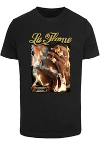 Melna kokvilnas T-kreklā ar grafiku, kurā attēlots figūra ar liesmām, zelta teksts "La Flame" un sudraba rotājumi dizainā.