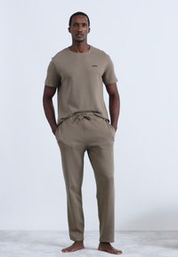 Barna, bordázott anyagból készült lounge szett; rövid ujjú póló kis logóval, összeillik a húzózsinóros, laza szabású nadrággal.