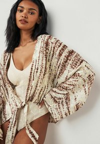 Luftig, mønstret kimono med knyt foran, prydet med jordfarver i brune nuancer på en lys baggrund, fremstillet af blødt, let stof.