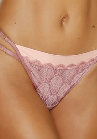 Spitzen-Bikini in sanftem Pink mit gewelltem Saum, ausgestattet mit verstellbaren Seitenträgern und einem glatten, satinähnlichen Stoff mit zarter Textur.