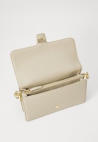 Beige bőr táska arany csattal. Nyitott dizájnnal, belső cipzáros zsebbel és sima felülettel rendelkezik. Tiszta, minimalista stílus.