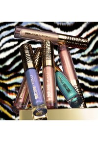 Seks Just Cavalli x KIKO Milano lipglosser i metalliske nyanser med zebramønstrede hetter på en matchende zebra-stripet bakgrunn.