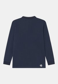 Námořnická modrá polo tričko s dlouhým rukávem, s žebrovanými manžetami a malým bílým logem blízko spodního lemu na zadní straně.