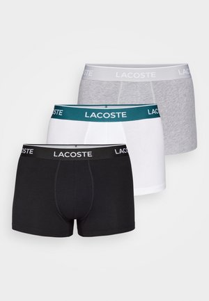 Pacote de três boxers Lacoste: preto, branco e cinza. Cada um apresenta uma faixa elástica contrastante com texto do logótipo, um design ajustado e tecido suave.