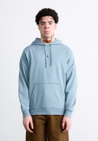 Sudadera de color azul claro hecha de una tela suave, con un bolsillo tipo canguro y capucha ajustable con cordón. Presenta un pequeño logo negro en el pecho.