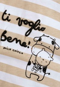 Beige og hvid stribet stof prydet med sort broderet tekst "ti voglio Bene!" og en ilustration af en ko, der holder en lille bjørn.