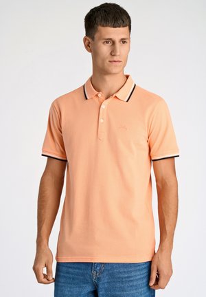 Polo a maniche corte di colore arancione chiaro con colletto e maniche a righe nere e bianche. Presenta una pattina con tre bottoni e un dettaglio del logo.