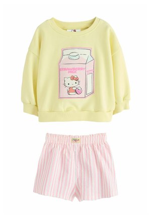 Żółty top z długim rękawem z Hello Kitty trzymającą truskawkę na różowym nadruku kartonowym, w zestawie z różowo-białymi pionowo paskowanymi elastycznymi szortami.