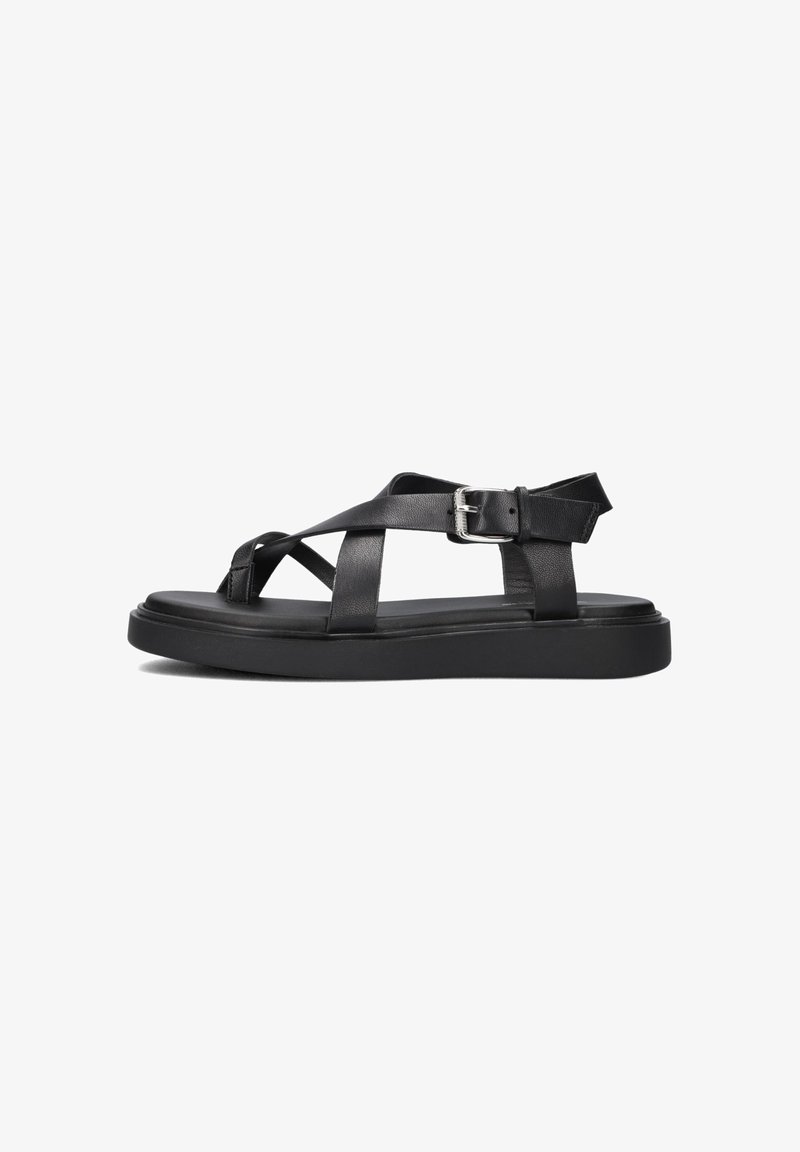 Black leather sandal featuring cross straps and a buckle closure, set against a white background, highlighting its minimalist design.